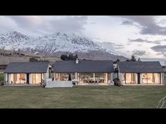 a large house sitting on top of a lush green field next to a snow covered mountain