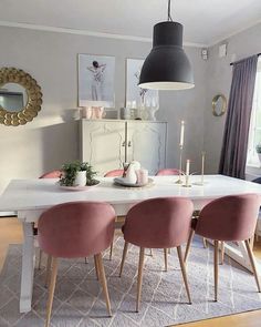 a dining room table with pink chairs around it