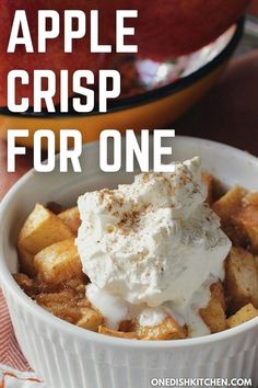 an apple crisp for one in a white bowl with cinnamon and whipped cream on top