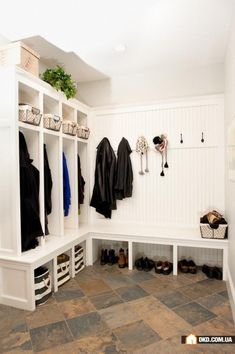 a mud room with several coats hanging on the wall