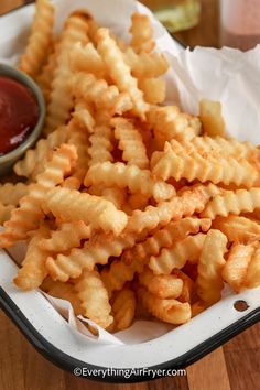 a basket filled with cheesy fries next to ketchup on a table