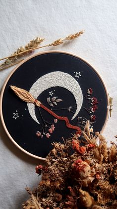 a black and white embroidered wall hanging next to dried flowers