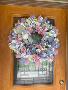 a door with a wreath made out of paper flowers and a stuffed animal on it