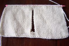 a piece of white knitted material on a wooden table with pink thread and scissors