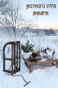 a wooden bench sitting in the snow with a hat on it's head and other items