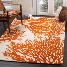 an orange and white area rug in front of a window with a chair on the floor