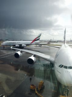 an airplane is parked on the tarmac with other planes in the background and cloudy skies