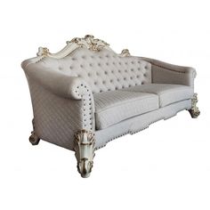 a white couch with gold trimmings on the arm and back, sitting against a white background