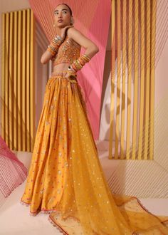 This stunning lehenga in rich look, embellishment and elongated butti detail come together in a flowing lehenga. The feminine blouse uses exquisite zardosi detail to enhance the neck, give this a younger feel. Festive Silk Lehenga With Dabka Work, Eid Embellished Silk Lehenga, Wedding Silk Lehenga With Mirror Work, Embellished Georgette Lehenga, Embellished Georgette Lehenga For Designer Wear, Designer Embellished Georgette Lehenga, Silk Lehenga With Dabka Work For Reception, Bollywood Style Embellished Raw Silk Lehenga, Reception Embellished Georgette Lehenga