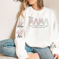 Custom Easter Mama Sweatshirt With Kids Names, This Mama Wears Her Bunnies On Her Arms Crewneck Sweatshirt, Mama Easter Sweatshirt Processing Time is 2 weeks. Processing time does not include shipping which is an additional 3-5 business days. Upgrade shipping options available at check out. This shirt is unisex cotton/polyester blend crewneck sweatshirt. All styles are super soft. Shirt sizes range from Adult S to 3XL. Size availability will vary. If the size you choose is out of stock with our White Long Sleeve T-shirt With Lettering, White Long Sleeve Tops With Lettering, Casual Tops With Name Print For Loungewear, Spring Long Sleeve Tops With Lettering, Crew Neck Top For Mother's Day Loungewear, Crew Neck Top For Loungewear On Mother's Day, White Cotton Sweater With Name Print, Crew Neck Top For Loungewear, White Long Sleeve Sweater With Name Print