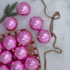 purple glass ornaments in a basket on a white marble counter top next to a christmas tree ornament