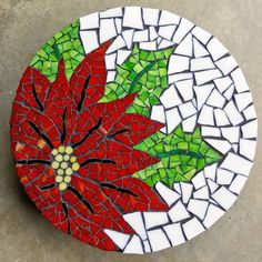 a red and green poinsettia sitting on top of a white tile table