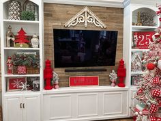 a living room with christmas decorations on the shelves and a flat screen tv mounted above it