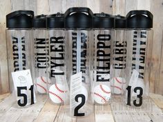 four plastic water bottles with baseballs and numbers on them sitting on a wooden table