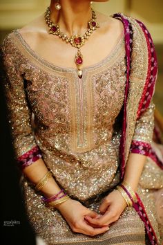 a woman sitting down wearing a gold and red wedding dress with her hands in her pockets