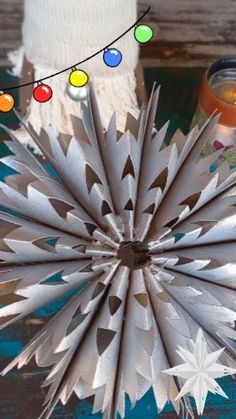 a close up of a paper star decoration on a table with candles and decorations around it