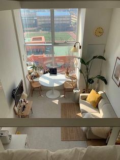 a living room filled with furniture and a large window overlooking a soccer field in the distance