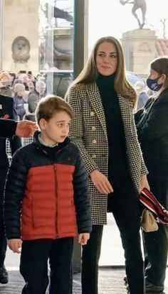 the young boy is walking next to his mother in front of an entrance with other people