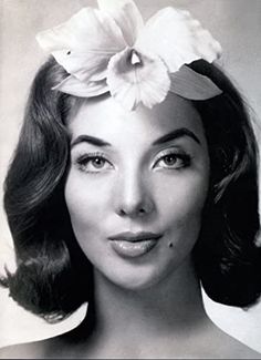 an old black and white photo of a woman with flowers in her hair