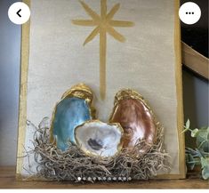 two seashells sitting on top of a wooden table next to a cross and potted plant