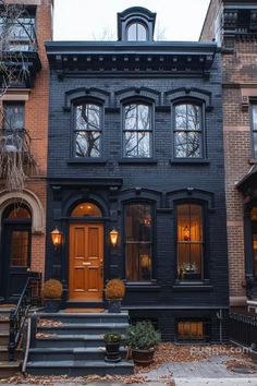 an old black house with stairs leading up to the front door and two story windows