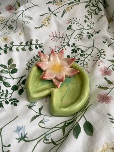 a ceramic planter sitting on top of a white tablecloth covered in floral designs