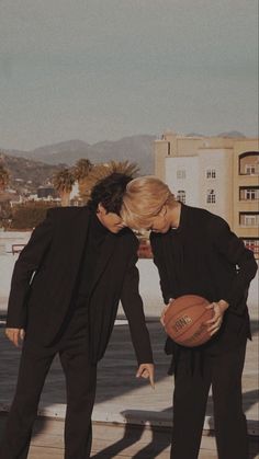 two people in black suits holding a basketball