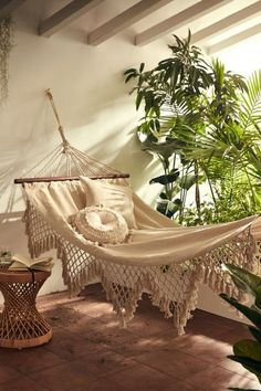 a hammock hanging in a room with potted plants