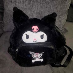 a black and white cat purse with pink eyes on it's face, sitting on a couch