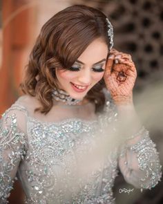 a woman in a silver dress holding her hand up to her face