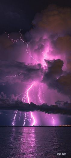 purple lightning strikes over the ocean on a cloudy night with dark clouds and bright lights