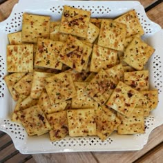 a white plate topped with lots of crackers on top of a wooden table