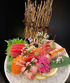 a plate with sushi and other food on top of ice cubes next to bamboo sticks