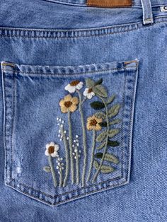 the back pocket of a pair of jeans with embroidered flowers