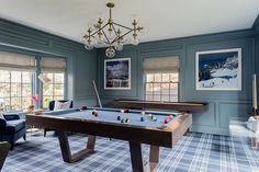 a pool table in the middle of a living room with blue walls and plaid carpet