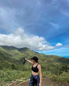 a woman standing on top of a lush green hillside