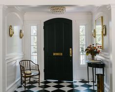 a black and white checkered floor with a chair in front of a door that has a chandelier above it