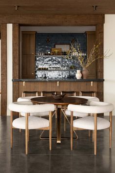 a dining room table with four chairs around it and a bar in the back ground