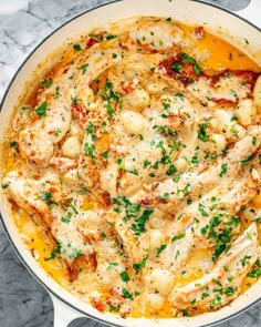 a large pot filled with pasta and chicken covered in sauce on top of a marble counter