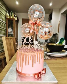 a birthday cake with pink icing and balloons in the shape of numbers on top