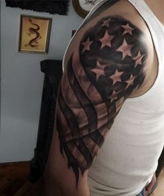 a man wearing a white tank top with an american flag tattoo on his arm and shoulder