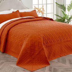 an orange quilted bedspread with white pillows