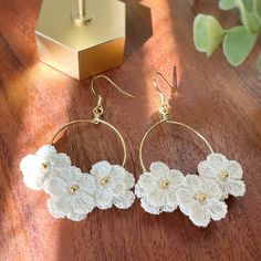 white crochet flower earrings sitting on top of a wooden table