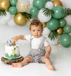 a baby boy sitting in front of a cake