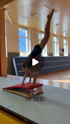 a woman doing a handstand on a balance beam in an indoor gym area