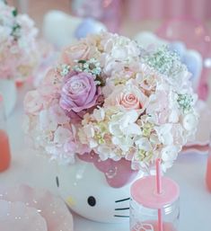 a hello kitty themed table setting with pink and white flowers