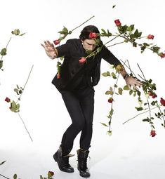 a man in a tuxedo with roses around his neck and hands out to the side