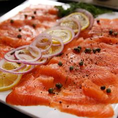 salmon with onions and lemon slices on a white plate