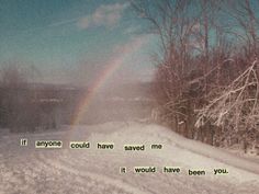 there is a rainbow in the sky over a snowy road with trees and snow covered ground