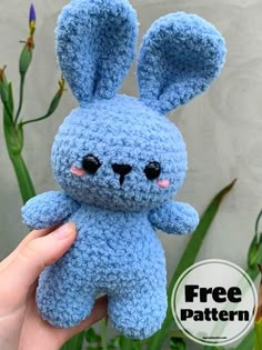 a small blue crocheted stuffed animal sitting in front of a plant with the caption free pattern